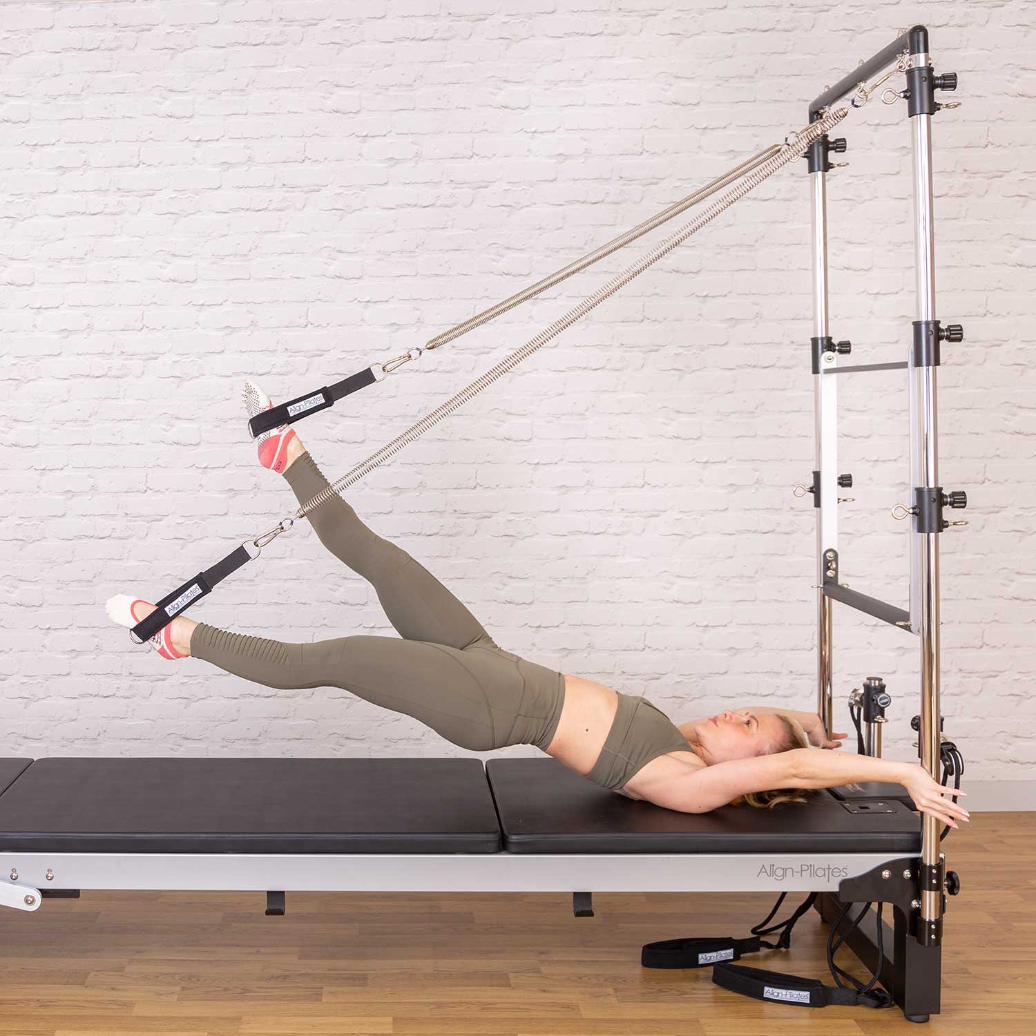 Frau trainiert auf dem Align Pilates Half Cadillac mit Federzügen am Reformer