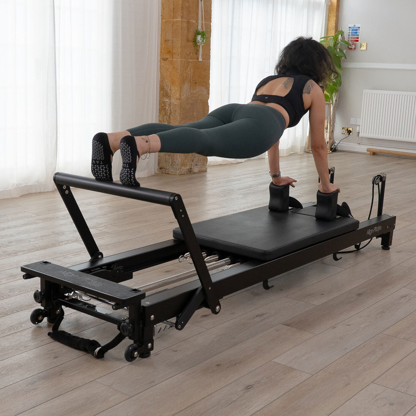 Frau in Plank-Position auf dem Align Pilates C8-Pro Reformer in Noir