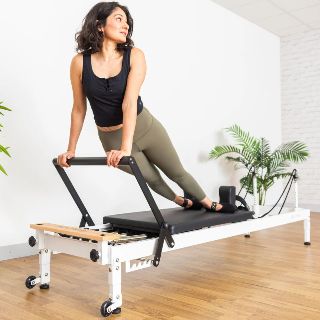Frau trainiert am Align Pilates R8-Pro Reformer mit weißem Rahmen