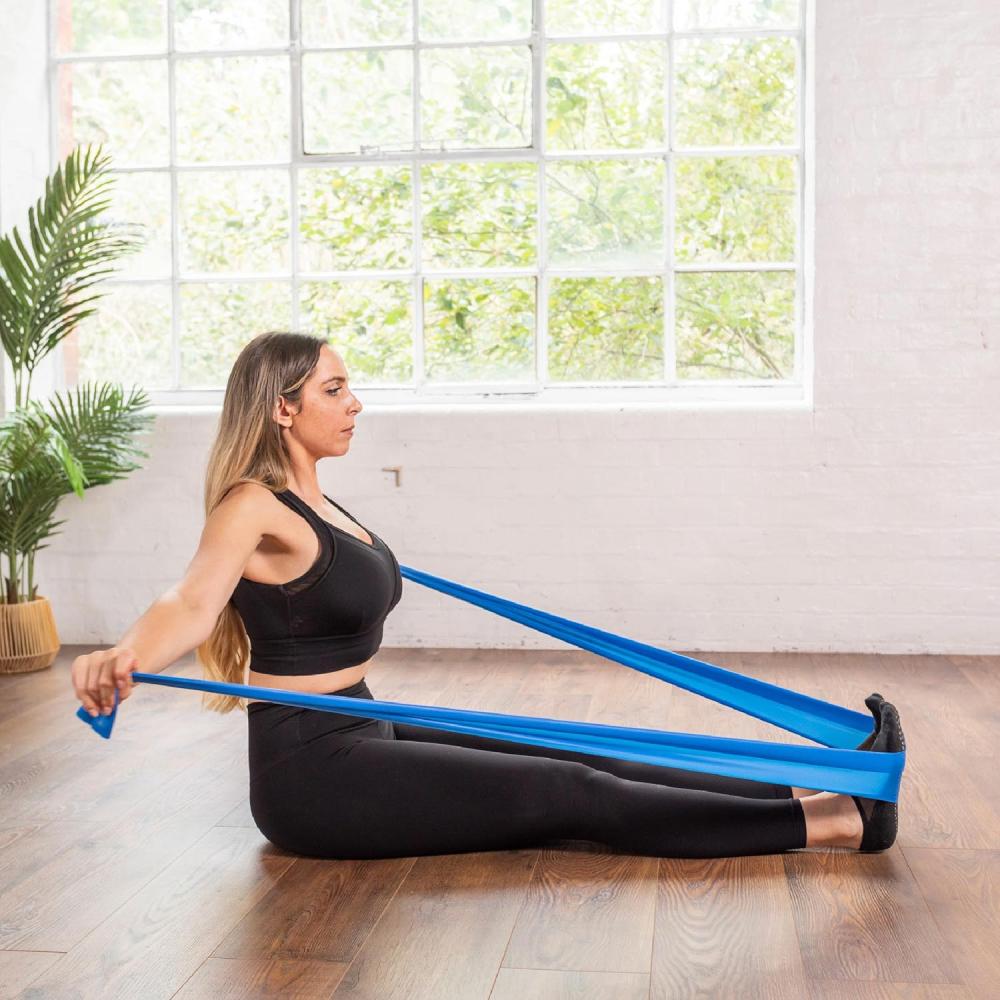 Frau trainiert sitzend mit dem blauen Align Pilates Widerstandsband Level 2 Medium