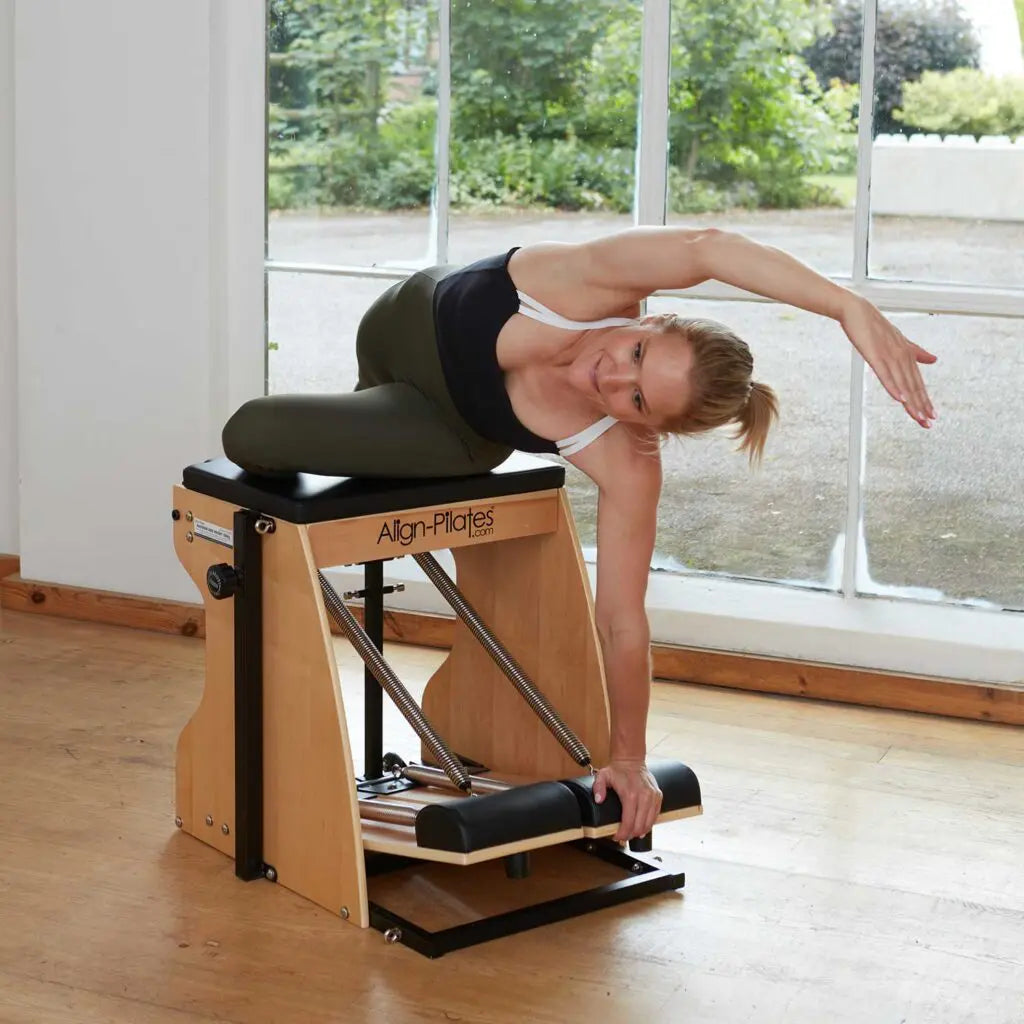 Frau trainiert am Align Pilates Combo Chair mit montierten Federn